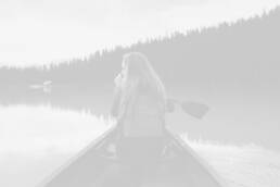 A woman sitting in a canoe on the water.